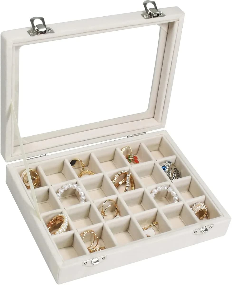 beige velvet jewelry box with glass lid full of rings
